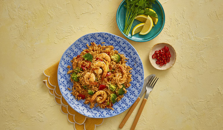 One Pot Spicy Rice served on a blue plate with fresh lemons and parsley